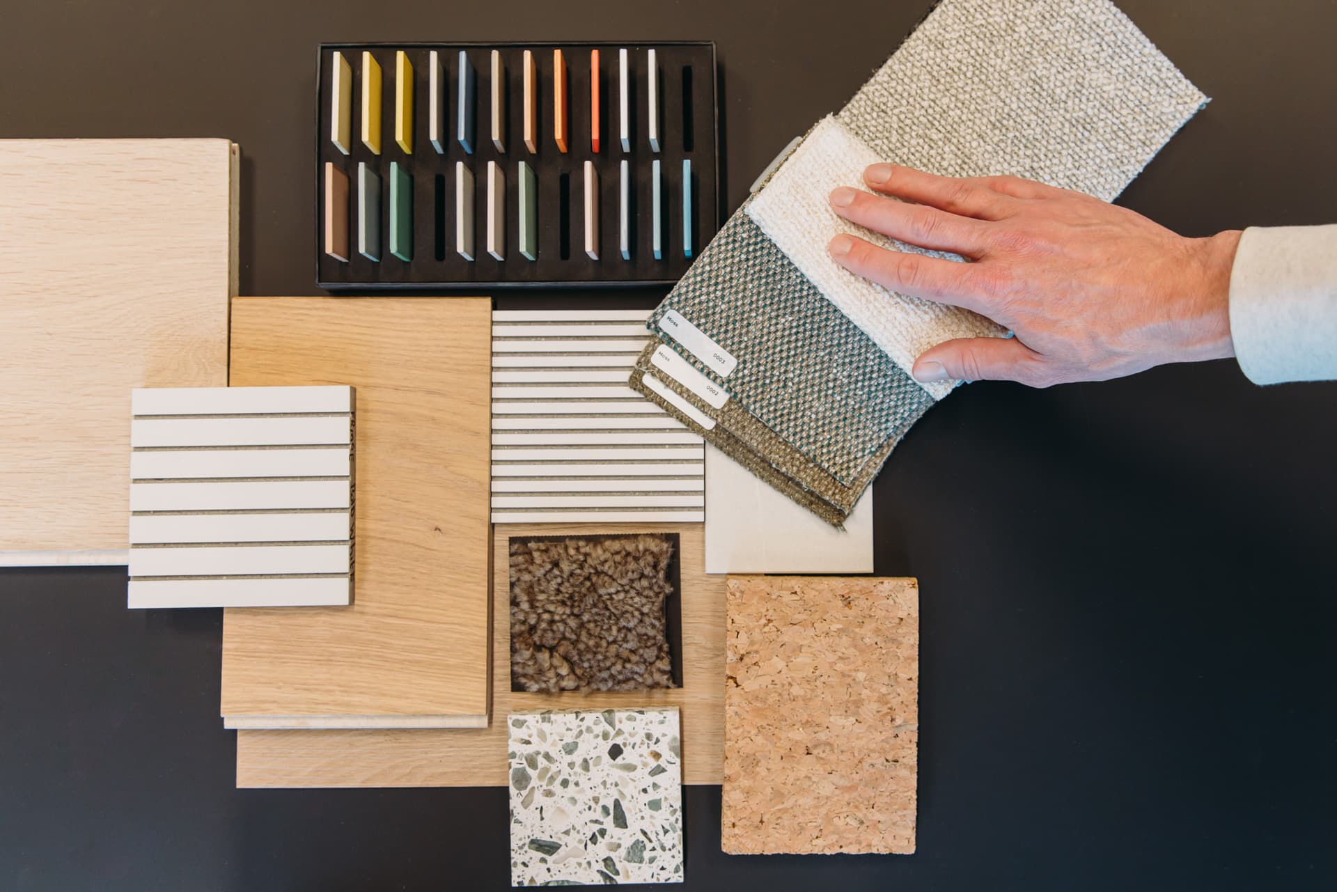 Materiaal op een tafel met wijzende hand naar stoffen